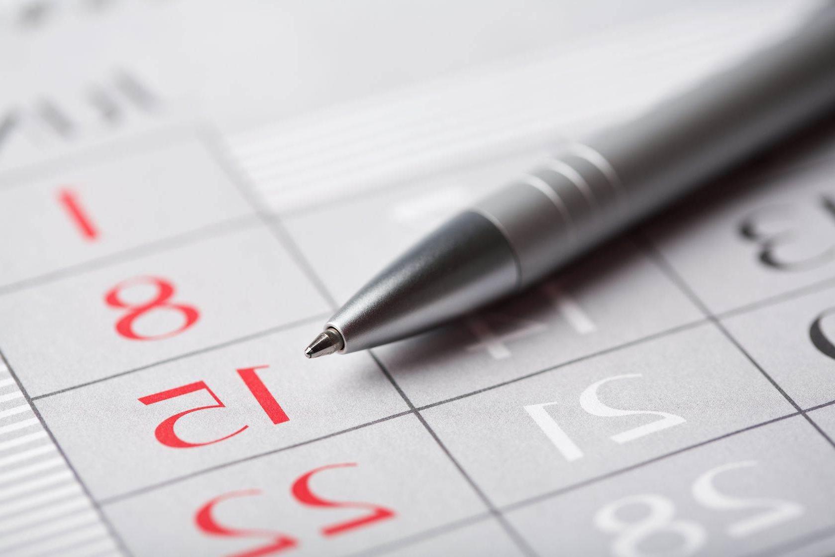 Close up of a pen on a calendar with focus on the 15th.